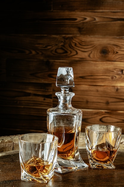 Two glasses of brandy or cognac and bottle on the wooden table