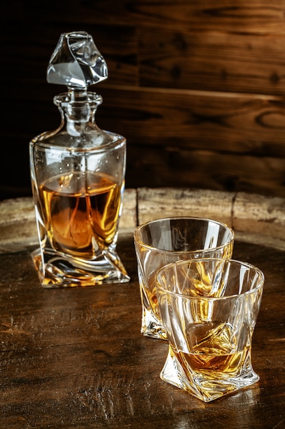 Two glasses of brandy or cognac and bottle on the wooden table