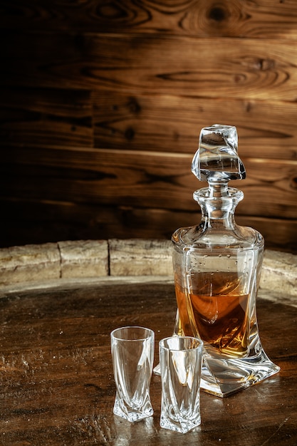 Two glasses of brandy or cognac and bottle on the wooden table