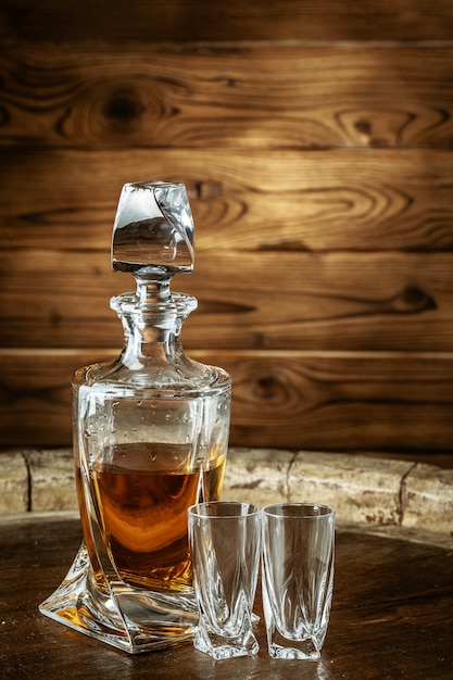 Two glasses of brandy or cognac and bottle on the wooden table