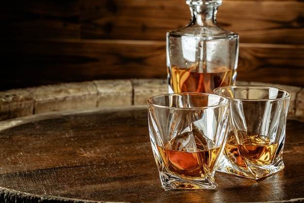 Two glasses of brandy or cognac and bottle on the wooden table