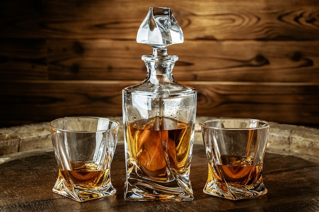 Two glasses of brandy or cognac and bottle on wooden table