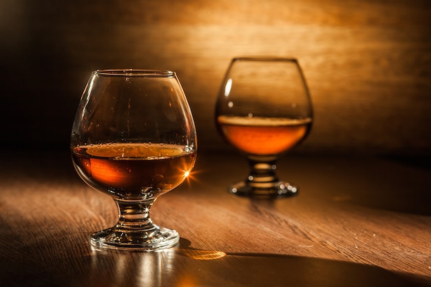 Two glasses of brandy on the wooden table.