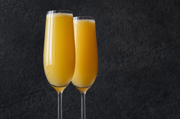 Two glasses of Buck's Fizz cocktail on black background