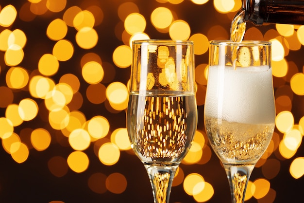 two glasses of champagne against shiny bokeh lights background