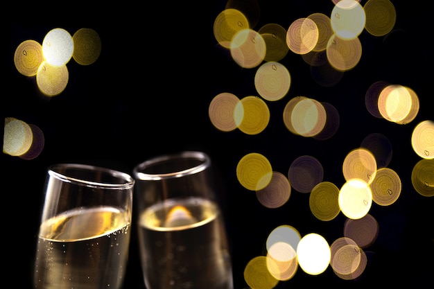 Two glasses of champagne on black background with blurred lights Festive concept