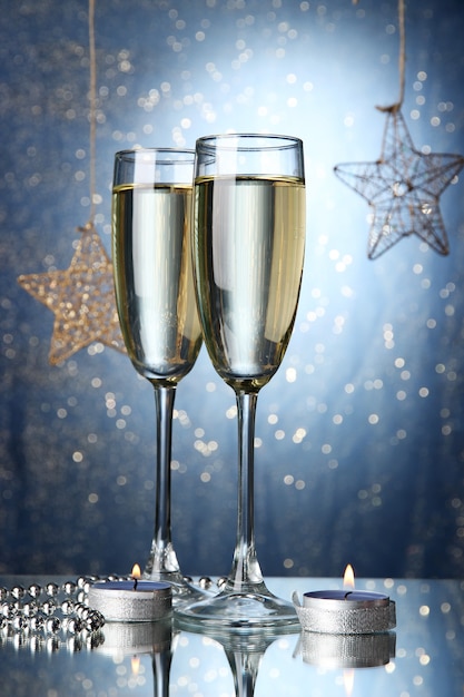 Two glasses of champagne on bright background with lights