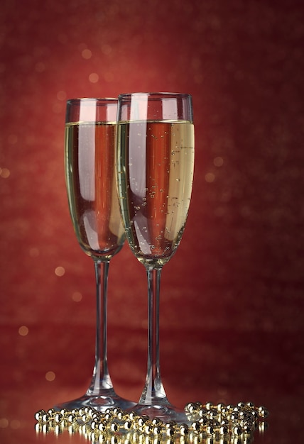 Two glasses of champagne on bright background with lights