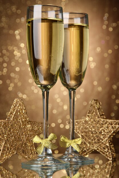 Two glasses of champagne on bright background with lights