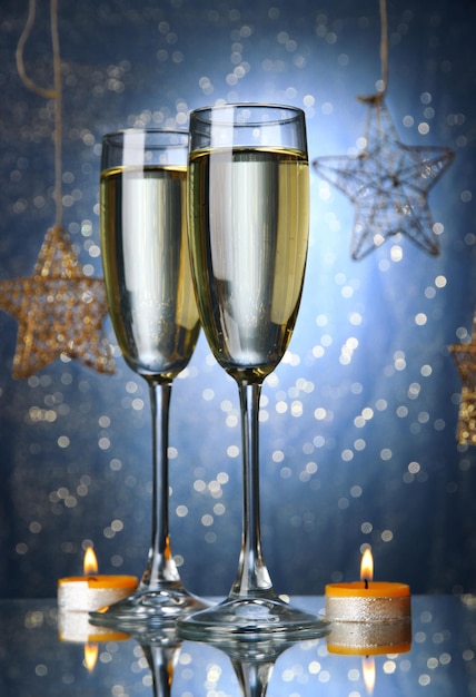 Two glasses of champagne on bright background with lights