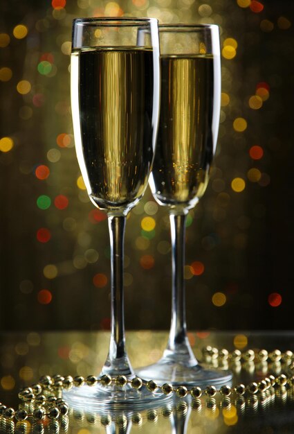 Two glasses of champagne on bright background with lights