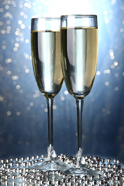 Two glasses of champagne on bright wall with lights