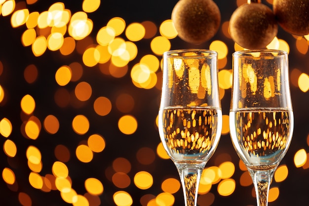 Two glasses of champagne and Christmas baubles on shiny bokeh lights