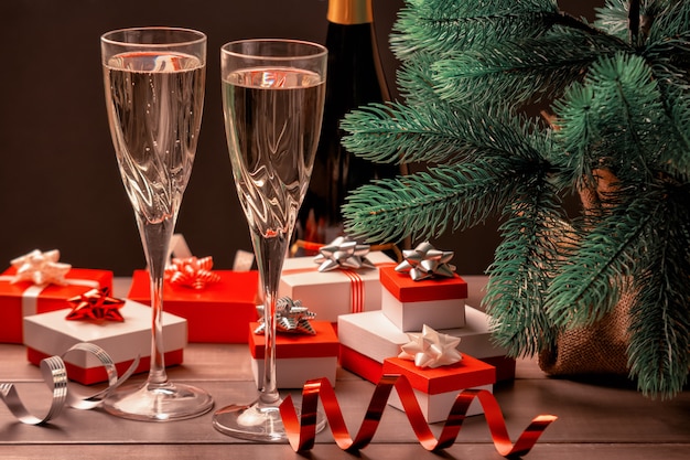 Two glasses of champagne, a lot of gift boxes with bows and decorative ribbons. 