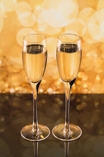 Photo two glasses of champagne with golden light bokeh on background. romantic dinner. winter holiday concept.