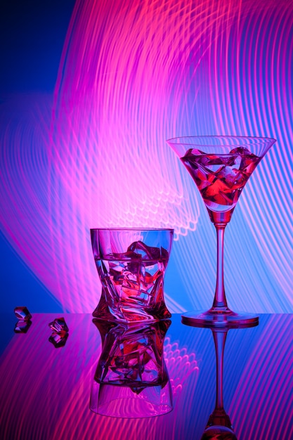 Two glasses a cocktail martini whisky ice, against the blue of beautiful light effects