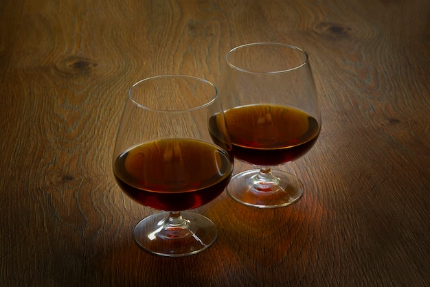 Два стакана коньяка на деревянном столе