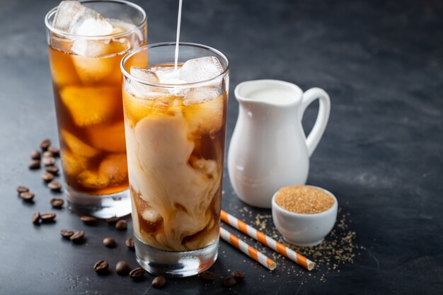 Two glasses of cold coffee on a dark background.