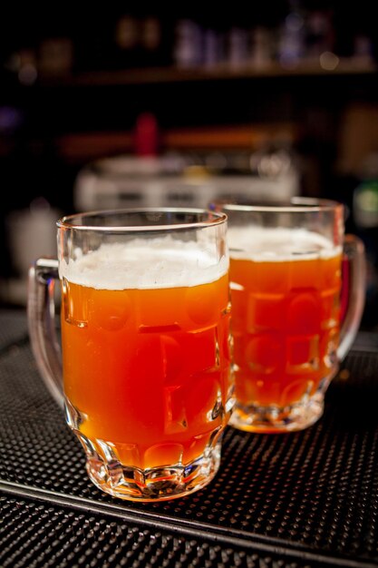 グラス2杯ゴールデンビール黒背景ホリデーイベントラグジュアリーライフドリンクナイトエールフォーム。オクトーバーフェストの美しい背景。ソフトフォーカス。黒の背景にラガー2杯。