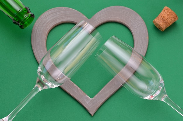 Two glasses and a heart-shaped frame on a green background