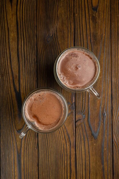 Two glasses of hot chocolate on a wooden table