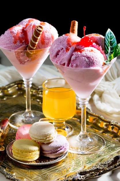 Two glasses of ice cream with a strawberry and vanilla ice cream on a tray.