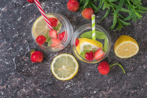 Due bicchieri di acqua ghiacciata, bacche di limone e menta