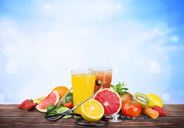 Two glasses of juice with fruits and vegetables on blurred light background