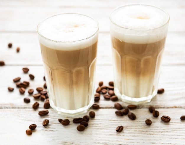 Two glasses of latte coffee and coffee beans