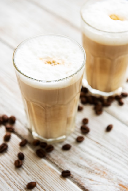 Two glasses of latte coffee and coffee beans