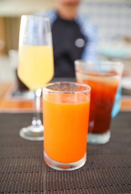 Two glasses of orange juice on a table with one that says orange juice.