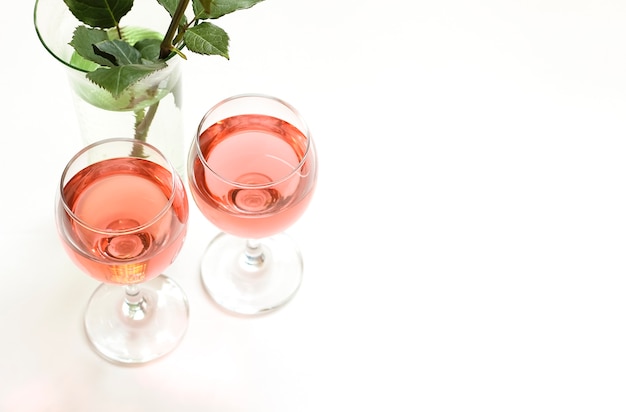 Sul tavolo ci sono due bicchieri di vino rosato.