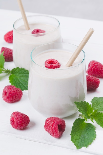 Two glasses of raspberry milkshake on wooden background