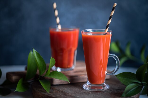 Two glasses of red homemade fresh tomato juice on dark rustic table, selective focus