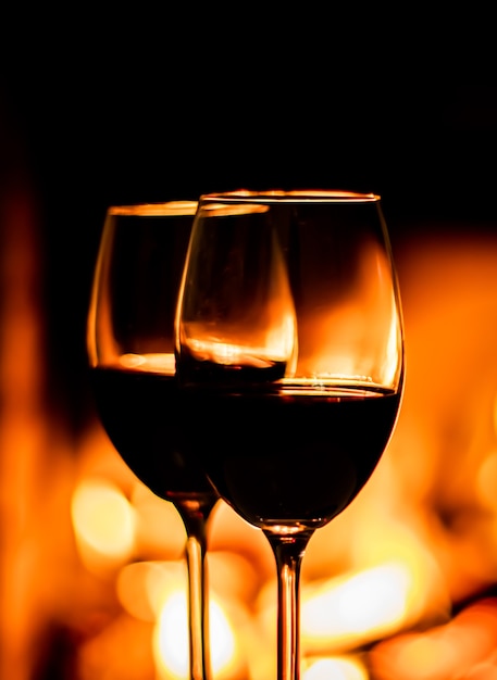 Two glasses of red wine on the background of fireplace lights