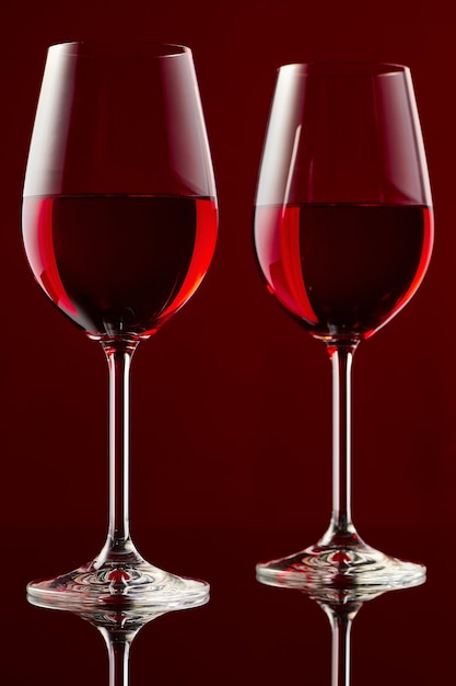 Two glasses of red wine on a glossy table.