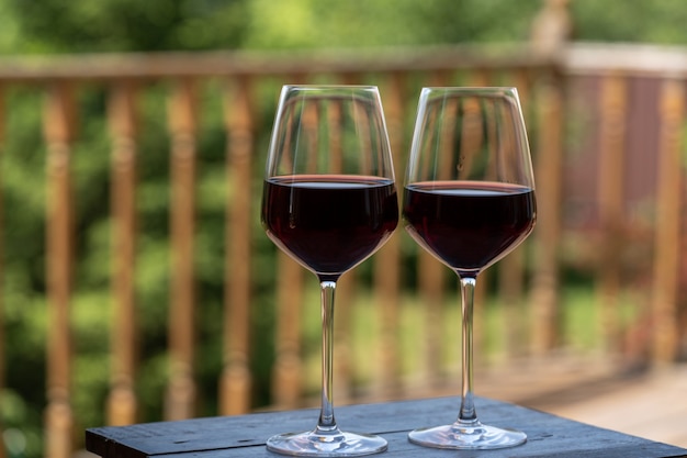 Two Glasses of red wine over green garden background.