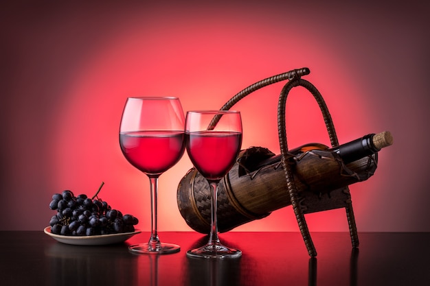 Two glasses of red wine and wine bottle on wooden table. Holiday concept. Wine drinking culture. Romantic background.