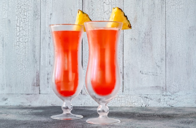 Two glasses of Singapore Sling on wooden wall