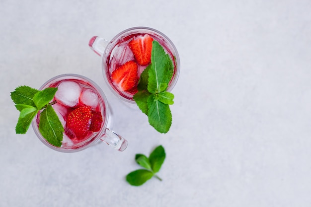 Due bicchieri di fragola estiva bevono con la menta su uno sfondo chiaro