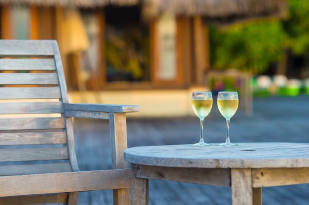 Two glasses of tasty white wine at sunset on wooden table