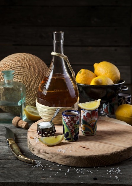 Two glasses of tequila with lemon and salt on a wooden tray