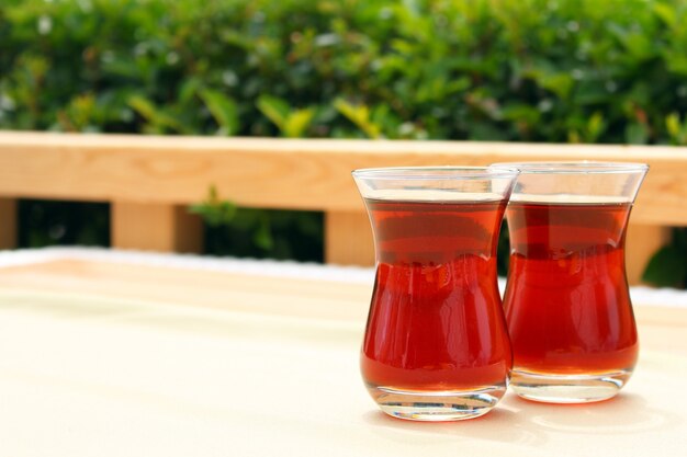 Two glasses of Turkish tea in traditional cup on wooden table.