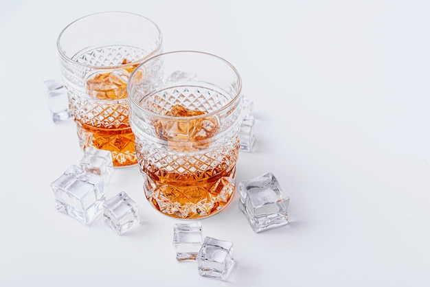 Two glasses of whiskey with ice on a white background with place for text