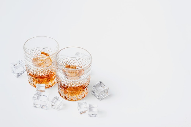 Two glasses of whiskey with ice on a white background with place for text