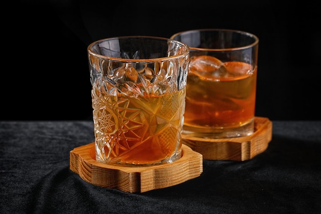 Two glasses of whiskey with ice on a wooden board