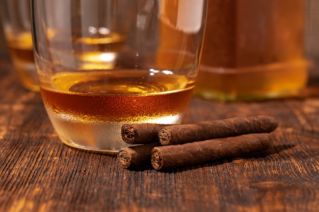 Two glasses of whisky and cigars on wooden table