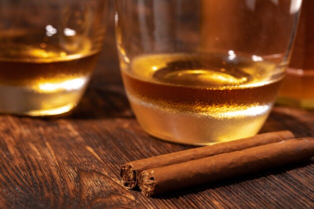 Due bicchieri di whisky e sigari sulla tavola di legno