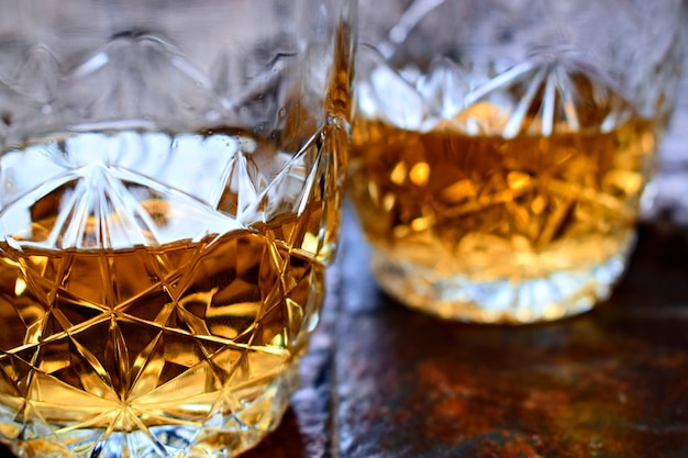 Two glasses of whisky on a old stone background.