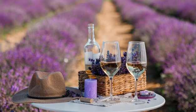 Two Glasses of white wine and bottle in a lavender field in Provance Violet flowers on the background